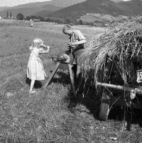 Man standing at the grindstone and girl cranked