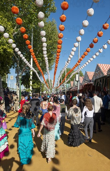 Spanish women with colorful flamenco dresses in front of marquees