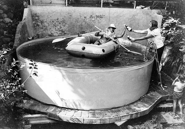 Man with lifejacket in inflatable dinghy in paddling pool