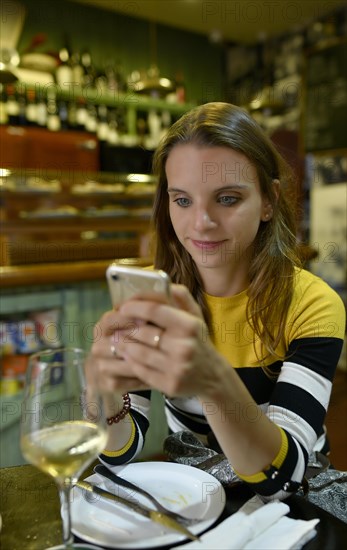 Young woman looks at her mobile phone in Tapas Bar