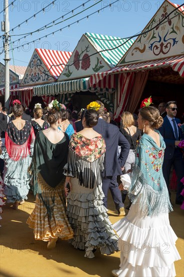 Spanish women with colorful flamenco dresses in front of marquees