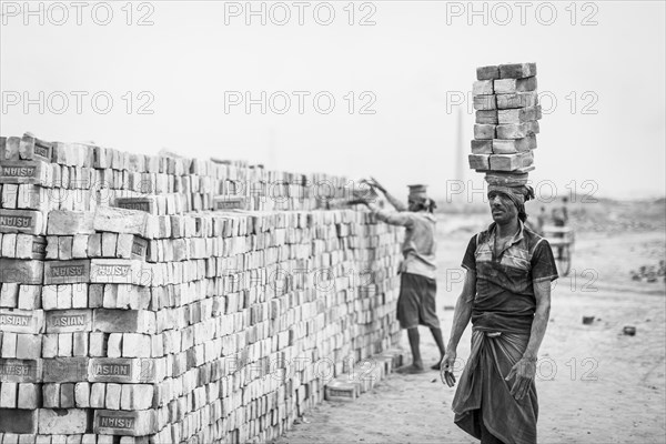 Workers with bricks on their heads in the brickyard