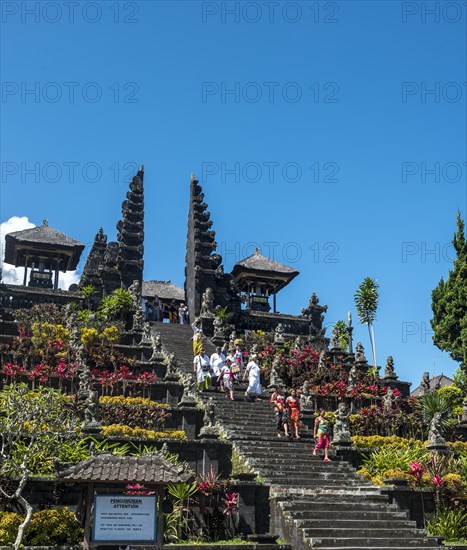 Balinese believers in traditional clothing go down stairs