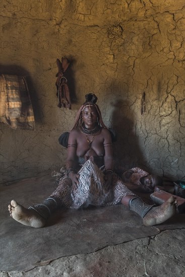 Woman of the Ovahimba or Himba people cleaning and disinfecting clothes and body