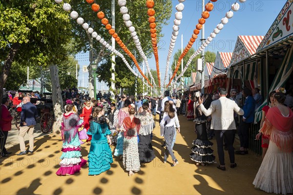 Spanish women with colorful flamenco dresses in front of marquees