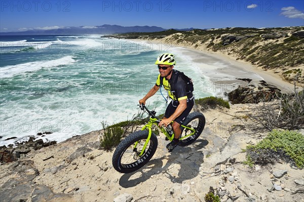 Mountainbiker with Fatbike on cliff