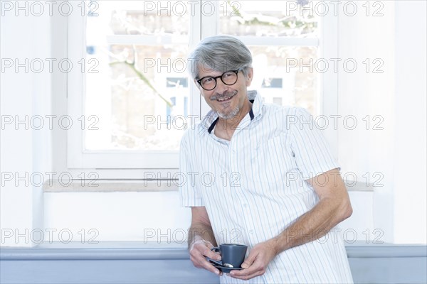 Man with coffee cup at his office window