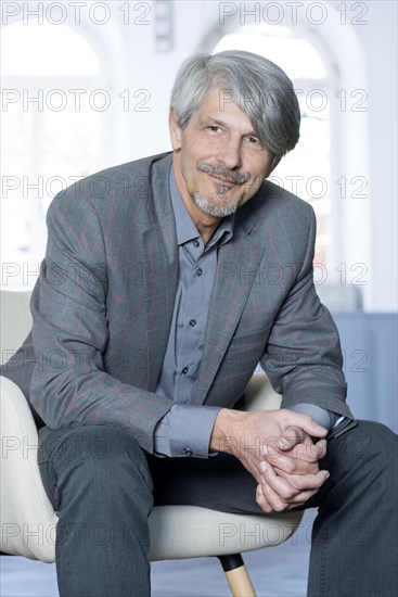 Man sits smiling in an armchair