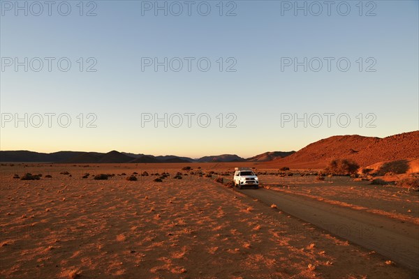 All-terrain vehicle drives on sandtrack in the evening light