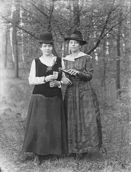 Two women with hat share a beer in the forest