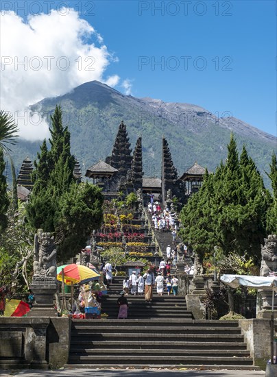 Balinese believers in traditional clothing go down stairs