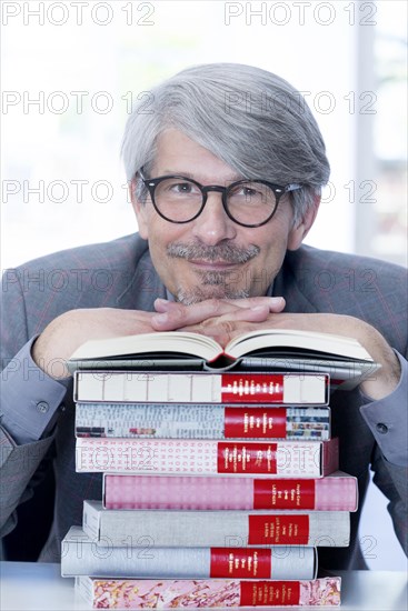 Man leaning on a book pile