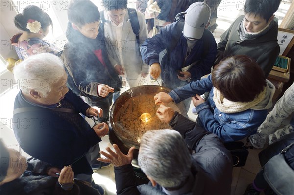 People lighting joss sticks in incense burner