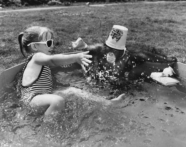 Girl and chimpanzee in paddling pool