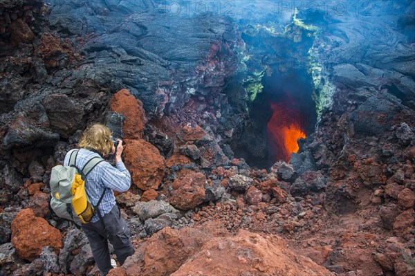 Tourist photographing an active magma stream below the Tolbachik volcano
