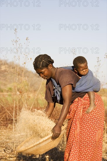 Tonga woman with child on her back sifting grains