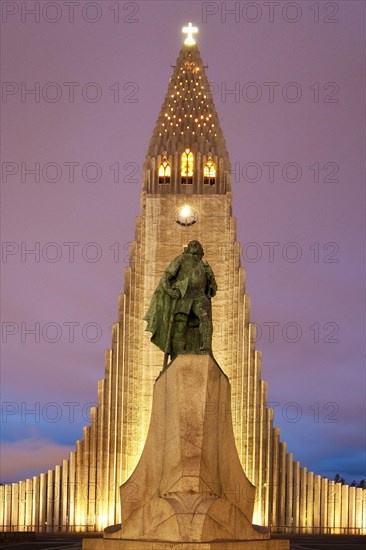 Illuminated Hallgrimskirkja with statue of Leif Eriksson at dusk