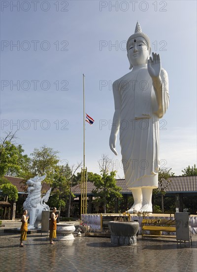 Monks in front of a gigantic Buddha statue in Wat Pa Thamma Utthayan