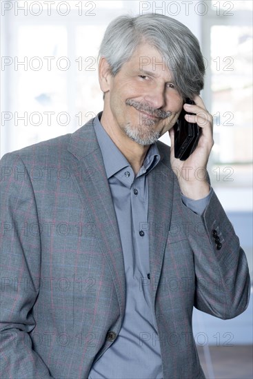 Man with mobile phone in front of his office window