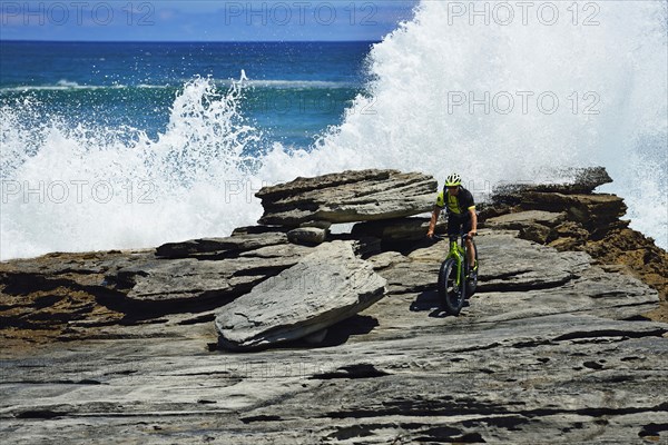 Mountainbiker with Fatbike on cliff