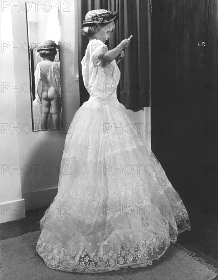 Child in white dress in front of a mirror