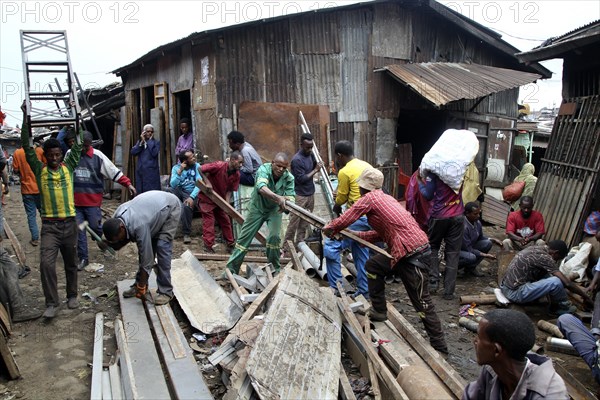 Men in front of corrugated-iron huts