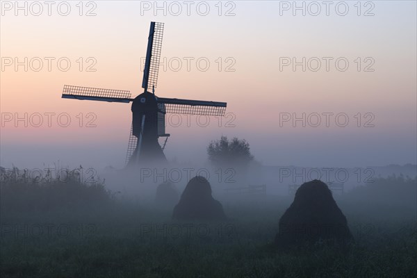 Historical windmill in the early morning mist at dawn