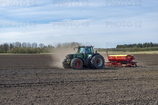 Tractor with seed drill working a field in spring