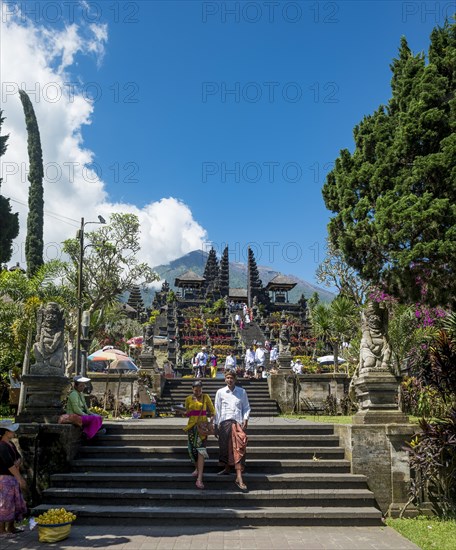 Balinese believers in traditional clothing go down stairs