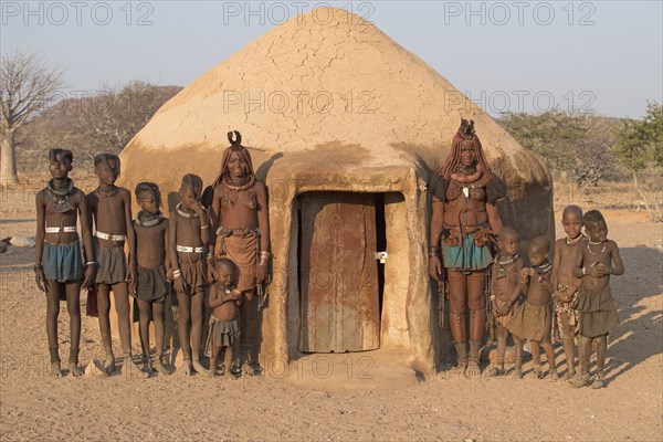 Himba women and children in front of a mud hut