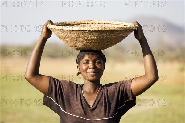 Tonga woman carries a basket with millet to her village at the Lake Kariba