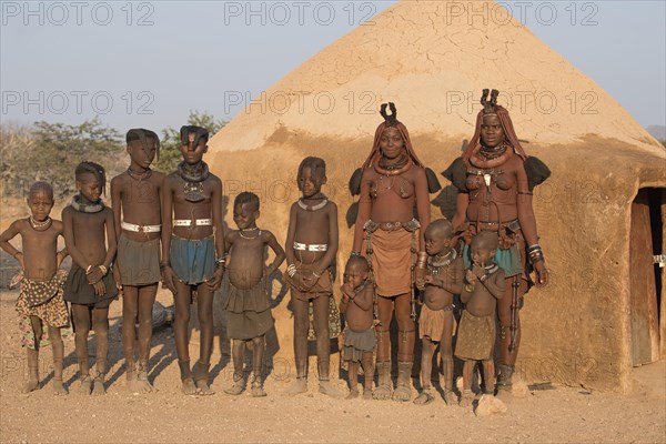 Himba women and children in front of a mud hut