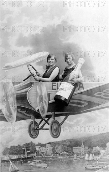 Two women with a bottle of sparkling wine in an aircraft mock-up