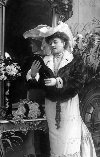 Woman with hat and fur looking at herself in mirror