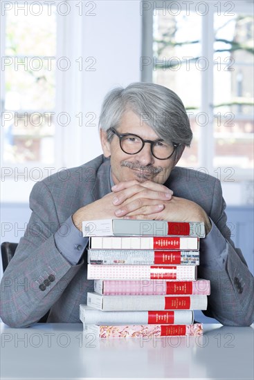 Man leaning on a book pile