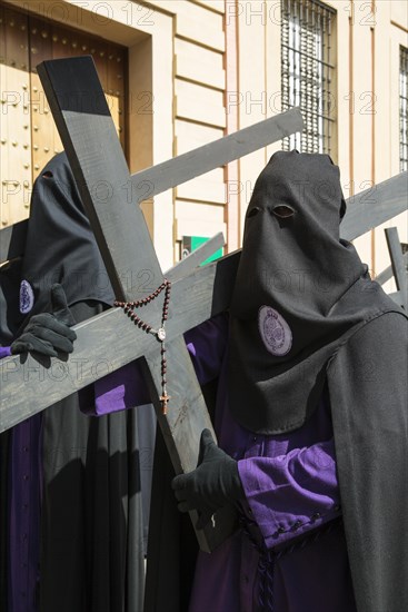 Penitents with cross and rosary at the Semana Santa