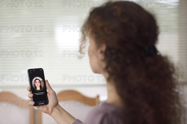 Woman with Apple iPhone X smartphone in her hand using Face ID