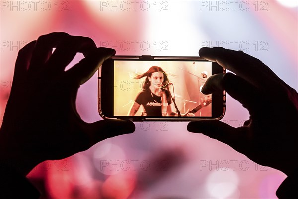 Fan taking photo with cellphone of musician