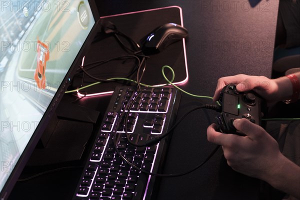 Hands of a player operate game controller over a keyboard