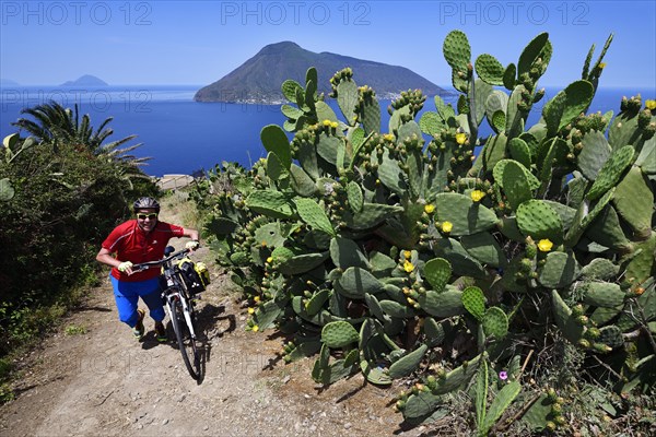 Cyclist at Punta del Legno Nero at Quattropani overlooking the island of Salina