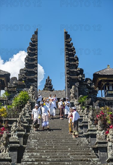 Balinese believers in traditional clothing go down stairs