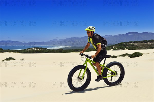 Mountain biker with fat bike in sand dunes