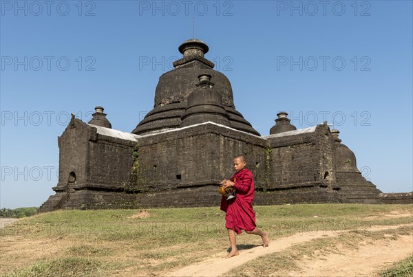 Novice Buddhist monk collects morning alms in front of Laymyetnha Paya