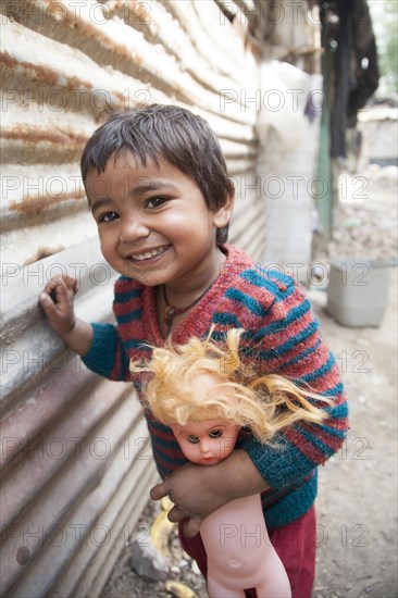 Laughing little child with doll in the slum at the Ghazipur garbage dump