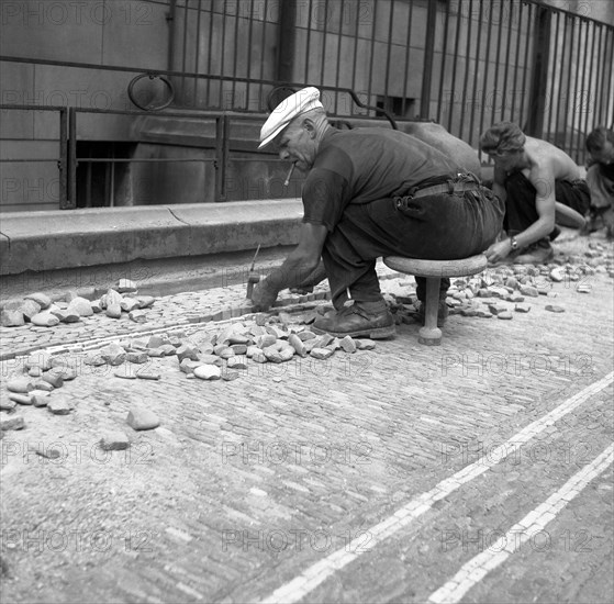 Road workers paving a road with natural stones