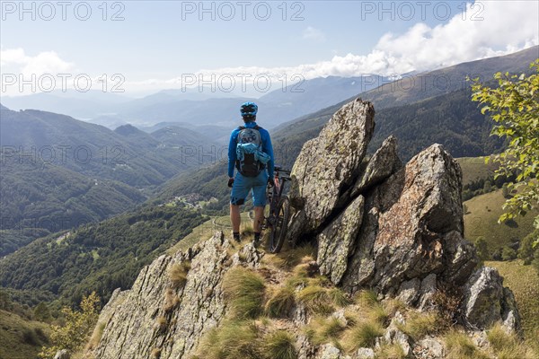 E-Mountainbiker enjoys the view from a mountain above Bogno