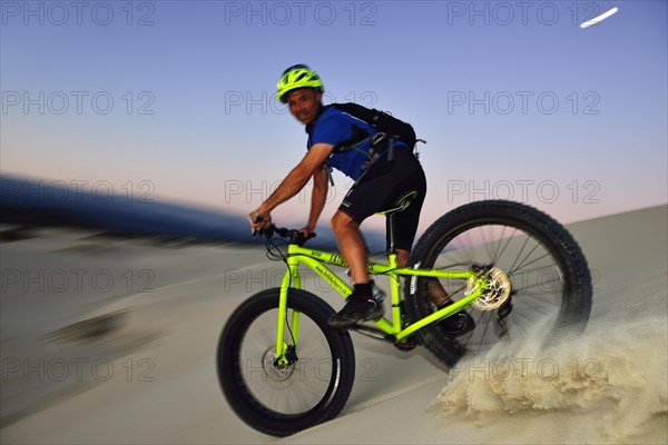 Cyclist with Fatbike descending sand dune