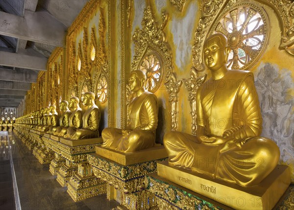 Row of golden Buddha statues in the corridor of the Phra Maha Chedi Chai Mongkhon Pagoda