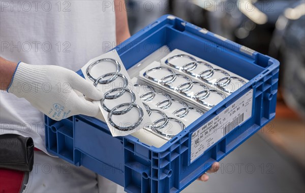 An Audi employee holds a box of Audi logos on the Audi A4 assembly line at the Audi AG plant in Ingolstadt