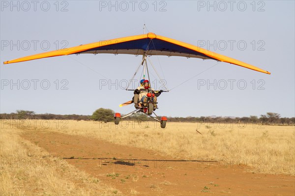 Ultra-light plane flying over sandy runway